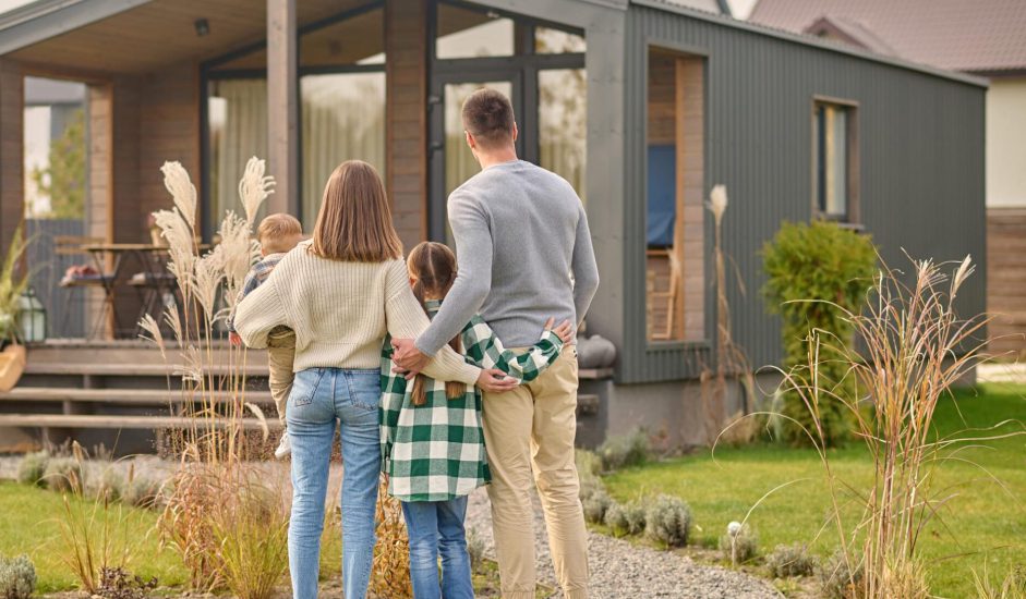 Back-view-of-family-hugging-and-admiring-their-home